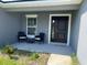 Covered front porch with black door and two wicker chairs at 943 Derbyshire Dr, Kissimmee, FL 34758