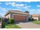 Tan house with a brown garage door and brick driveway at 125 Silver Maple Rd, Groveland, FL 34736