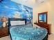 Bedroom with ocean-themed mural, dresser, and full-size bed at 8908 Legacy Ct # 201, Kissimmee, FL 34747