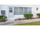 Exterior view shows a building with bright white facade, glass block window, and tidy landscaping at 100 El Camino Dr # 102, Winter Haven, FL 33884