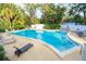 Inviting community pool with lounge chairs offers a refreshing escape surrounded by lush greenery at 100 El Camino Dr # 102, Winter Haven, FL 33884