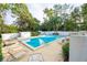 Inviting swimming pool surrounded by lounge chairs, lush greenery, and tall trees creating a private oasis at 100 El Camino Dr # 102, Winter Haven, FL 33884