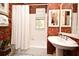 Bathroom with a pedestal sink, tub, and tropical wallpaper at 1821 Stanley St, Longwood, FL 32750