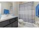 Clean bathroom with dark vanity, striped shower curtain, and tiled floor at 2583 Sedge Grass Way, Orlando, FL 32824