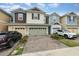 View of the townhome with a brick paved driveway and attached two-car garage at 2583 Sedge Grass Way, Orlando, FL 32824
