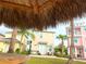 A view from beneath a tiki hut showcases the lush green space and colorful homes of the community at 3020 Latitude Ln, Kissimmee, FL 34747