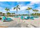 A hammock overlooking a sandy beach with palm trees, lounge chairs, and a pool on a sunny day at 3020 Latitude Ln, Kissimmee, FL 34747