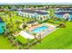 Aerial view of community pool surrounded by colorful townhomes, palm trees, and sun loungers at 3020 Latitude Ln, Kissimmee, FL 34747