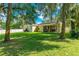 Spacious backyard with lush green lawn, mature trees, and a covered patio at 3442 Starbird Dr, Ocoee, FL 34761
