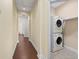 Hallway with wood floors leading to laundry room with stacked washer and dryer unit at 417 Pavia Loop, Lake Mary, FL 32746