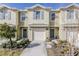 Tan two-story townhome with gray doors, attached garage, and landscaping at 54 Bella Oaks Dr, Port Orange, FL 32129