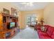 Living area with red couch, wooden media console, and view into bedroom at 9229 Lake Hickory Nut Dr, Winter Garden, FL 34787