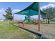 Community playground with a green slide and benches, shaded by a large canopy at 958 Anna Pl, Davenport, FL 33837