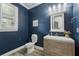 Stylish powder room with a vessel sink, wood vanity, and a contrasting dark blue accent wall at 10219 Atwater Bay Dr, Winter Garden, FL 34787