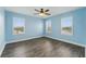 Light blue bedroom with wood-look flooring, ceiling fan, and natural light from three bright windows at 10219 Atwater Bay Dr, Winter Garden, FL 34787