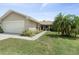 Tan house with white garage door and palm trees, a walkway to the entrance at 1423 Grand Cayman Cir, Winter Haven, FL 33884