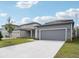 New construction home features a gray exterior, spacious garage, and a well-manicured lawn at 2437 Zuni Rd, St Cloud, FL 34771