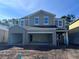 New two-story home with a large garage and gray siding awaits landscaping at 5238 Prairie Preserve Run, St Cloud, FL 34772