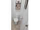 Cozy bathroom with white toilet, tile floors, decorative shelving and framed wall art at 7149 Dilly Lake Ave, Groveland, FL 34736