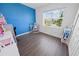 Bright bedroom with blue accent wall and laminate flooring and a view to the outside at 7149 Dilly Lake Ave, Groveland, FL 34736