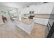 Modern kitchen with a large island, white cabinets, stainless steel appliances, and wood-look tile flooring at 7149 Dilly Lake Ave, Groveland, FL 34736