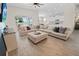 Open-concept living room with wood-look tile flooring and a large sectional sofa that extends to the kitchen at 7149 Dilly Lake Ave, Groveland, FL 34736
