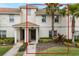 Inviting townhome featuring stucco walls, a tile roof, well-manicured lawn and mature palm trees at 9043 Dogleg Dr, Davenport, FL 33896
