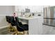 Kitchen area with white cabinets, bar seating, stainless steel appliances, and modern finishes at 219 Plumoso Loop, Davenport, FL 33897