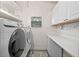 Functional laundry room boasts side-by-side washer/dryer and white cabinets for storage at 228 Westwood Dr, Leesburg, FL 34748