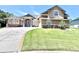 Inviting two-story home featuring manicured lawn, stone accents, and a circular driveway at 5210 Sailwind Cir, Orlando, FL 32810