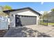 A spacious garage with a gray door and concrete driveway, complemented by exterior lighting and a nearby screened enclosure at 6121 Bass Hwy, St Cloud, FL 34771