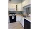 White kitchen with black appliances and light grey tile floors at 89 Crooked Pine Rd, Port Orange, FL 32128