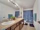 Bathroom featuring double sinks, wood cabinets and decorative shower curtains at 1317 Conch Key Ln, Davenport, FL 33837