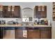 Close-up of the kitchen featuring dark wood cabinets, stainless steel appliances, and a double sink under an arched window at 1317 Conch Key Ln, Davenport, FL 33837