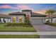 Charming single-story home with a tile roof, paver driveway, well-manicured lawn, and lush landscaping at dusk at 1511 Goblet Cove St, Kissimmee, FL 34746