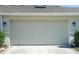 Attached garage with light beige door and exterior lighting at 15508 Blackbead St, Winter Garden, FL 34787