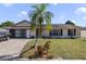 Charming single-story home featuring a well-manicured lawn, brick driveway, and mature palm tree in a sunny setting at 2537 Lanier Rd, Kissimmee, FL 34744