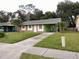 Single story home with stone facade, front lawn, and covered parking area at 417 Benita St, Kissimmee, FL 34744