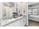 Bright bathroom with double sinks, granite counters, and a view into the cozy primary bedroom at 494 Amadoras Way, St Cloud, FL 34771