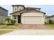 Two-story house with tan siding, a two-car garage, and a brick driveway at 494 Amadoras Way, St Cloud, FL 34771