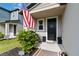 Inviting front porch with American flag, decorative shrubbery, and a dark-colored front door at 494 Amadoras Way, St Cloud, FL 34771