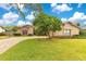 Tan house with a paved driveway, landscaping, and a large tree in the front yard at 615 Tuskawilla Point Ln, Winter Springs, FL 32708