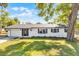 Charming single-story white brick home featuring manicured lawn and lush landscaping and dark trim at 720 Jasmine Ave, Orange City, FL 32763