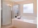 Relaxing bathroom with a large soaking tub, glass-enclosed shower, and frosted window at 1101 James Ave, Deltona, FL 32738