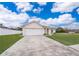 Tan house with white garage door, lush green lawn, and a driveway at 1101 James Ave, Deltona, FL 32738