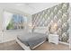 Bedroom with patterned wall, gray bedding, and white nightstands at 1551 Flange Dr, Davenport, FL 33896