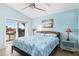 Main bedroom with light blue walls, a ceiling fan, and access to a balcony at 6110 S Atlantic Ave, New Smyrna Beach, FL 32169