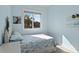 Light blue bedroom with a queen bed, window, and shelving at 6111 Turtlemound Rd, New Smyrna Beach, FL 32169