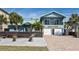 Two-story beach house with a teal exterior, a brick driveway, and a landscaped front yard at 6111 Turtlemound Rd, New Smyrna Beach, FL 32169