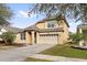 Two-story house with tan exterior, two-car garage, and landscaping at 7525 Azalea Cove Cir, Orlando, FL 32807